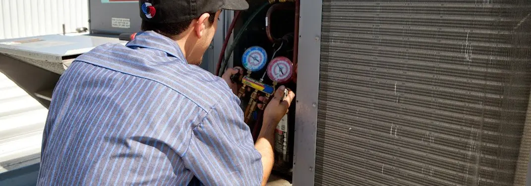 HVAC technician servicing a condenser unit in Newport